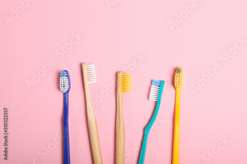 natural bamboo toothbrushes and plastic on a colored background top view.