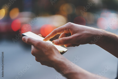 Close-up of male hands pointing finger on screen smart phone in city on the background  Businessman typing messages on her cellphone in the city center.