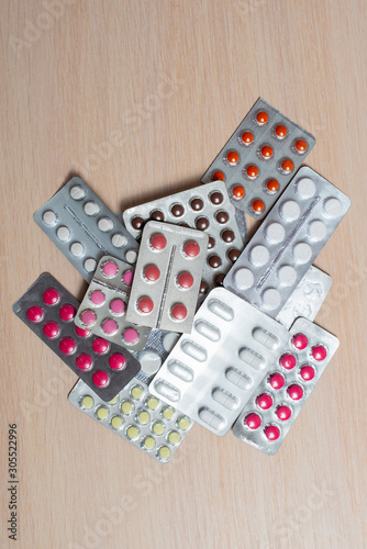 Blisters with multi-colored pills lie on a bright table. Medical flat lay.