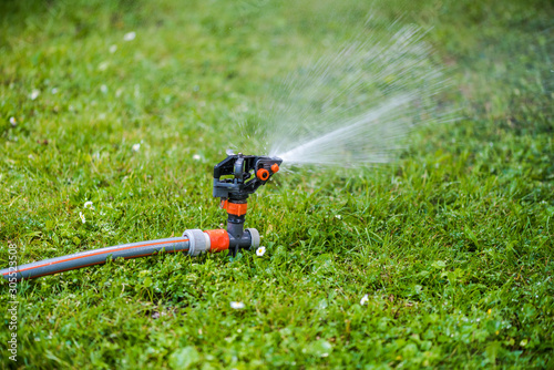 Lawn sprinkler system and green grass meadow