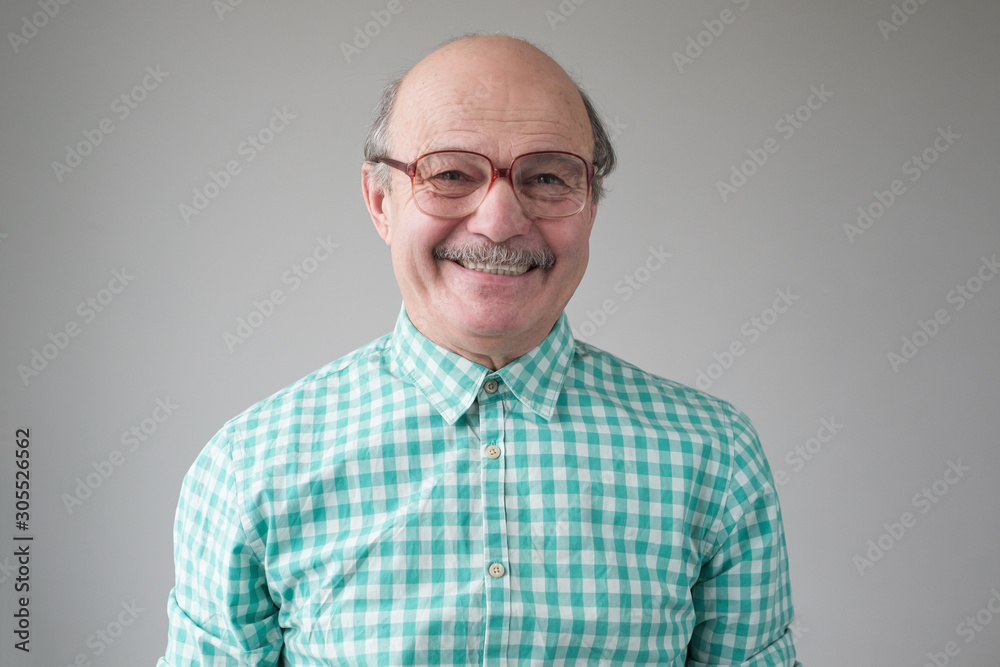 Happy senior man in funny glasses smiling at camera. Studio shot. Positive facial human emotion Happy senior man in funny glasses smiling at camera. Studio shot. Positive facial human emotion