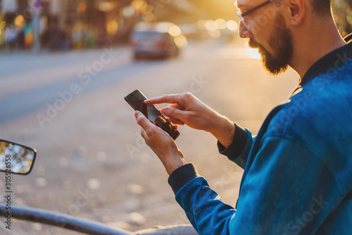 Pensive young man checking financial news on website connected to 4g wireless for surfing internet outdoors