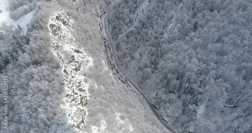 Aerial view of snow covered sunlit cliffs in the forest. Nature in winter time