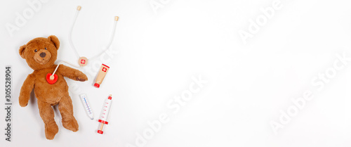 Fotografiet Teddy bear with toy stethoscope and toy medicine tools on white background