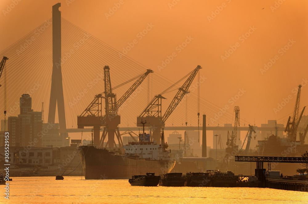 cranes in the port. Sunrise in Shanghai harbor. Huangpu river in early morning light.  Natural light but looks like b&w toned effect.