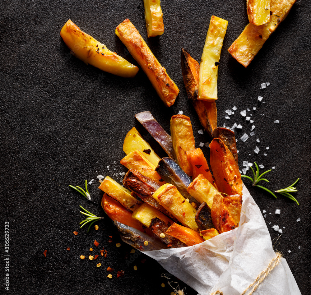 French fries, baked fries from different types and colors of potatoes  sprinkled with herbs and spices in paper bag on a black background, top  view, close-up. foto de Stock | Adobe Stock