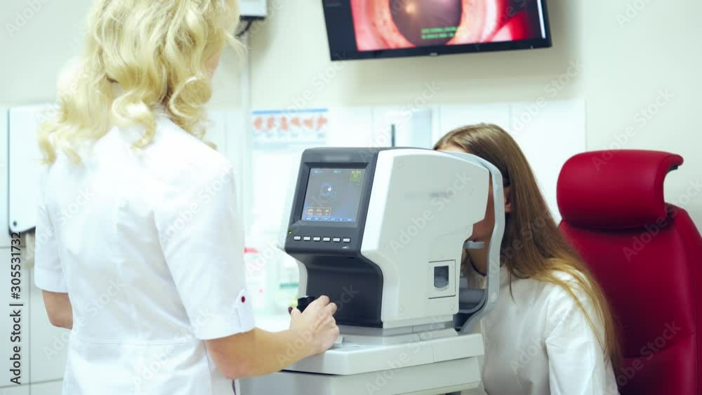 Doctor examining patient's eyes on modern device. Optometrist checks eyesight of a young woman with a refractometer in clinic. Doctor examining patient's eyes on modern device. Optometrist checks eyesight of a young woman with a refractometer in clinic.
