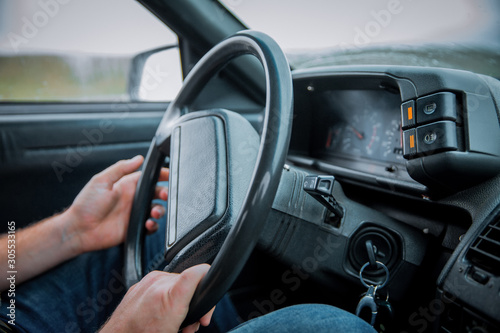 Car Interior. Male arms holding leathern rudder of car .the man grabs the steering wheel and drives the car. Black control panel in a old Russian car with a steering wheel . © Adil