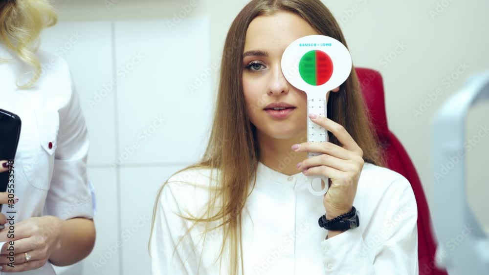 Young woman checking eyesight. Pretty girl doing vision test with one