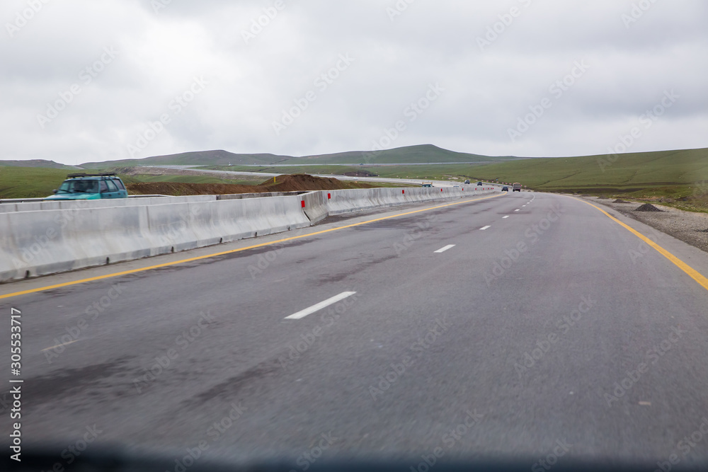 Fototapeta premium road receding into the distance in open countryside under a cloudy white sky with focus to the center white line . asphalt car road .wallpaper pattern landscape . Empty road white cloudy weather.