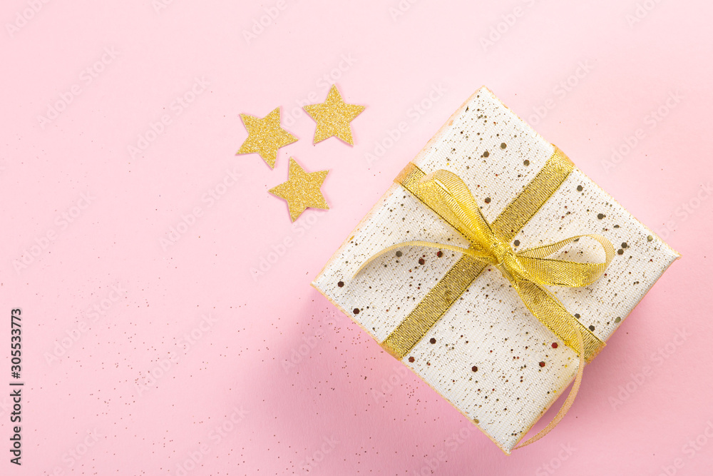 Selection of white, gold and black coloured christmas gift boxes on pink background