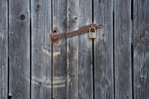 Detail of weathered planks of a shelter with a rusty padlock