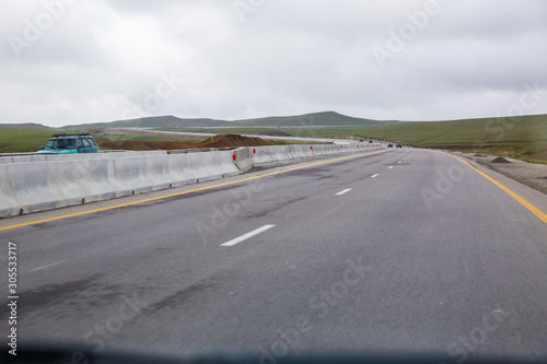 road receding into the distance in open countryside under a cloudy white sky with focus to the center white line . asphalt car road .wallpaper pattern landscape . Empty road white cloudy weather. © Adil
