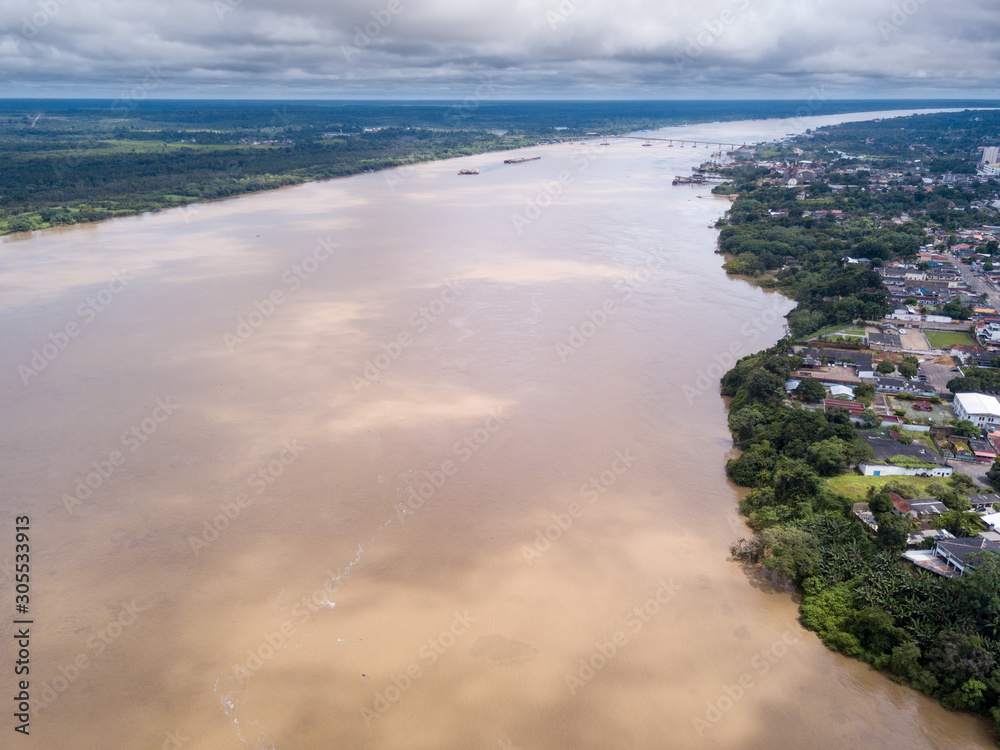 Aerial drone view of Madeira river, Porto Velho city center and Amazon rainforest in the background on cloudy winter day. Concept of environment, ecology, global warming, climate change and travel.