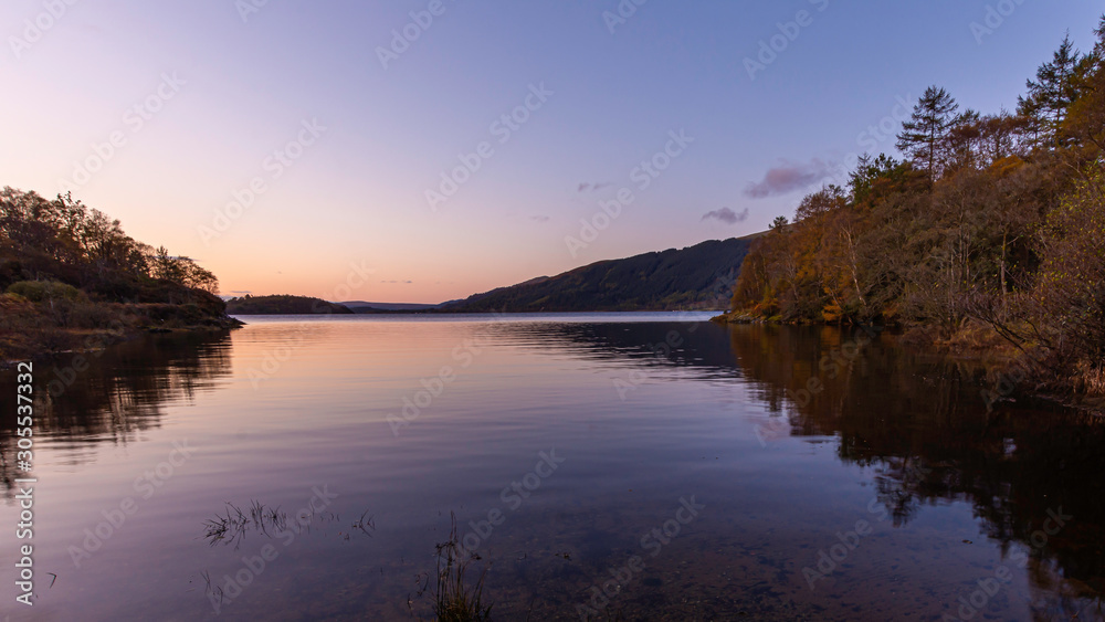 Sunrise at Loch Lomond, Scotland,UK..Beautiful landscape of Scottish Highlands.Tranquil morning scene with reflection of autumn coloured trees in calm lake surface.