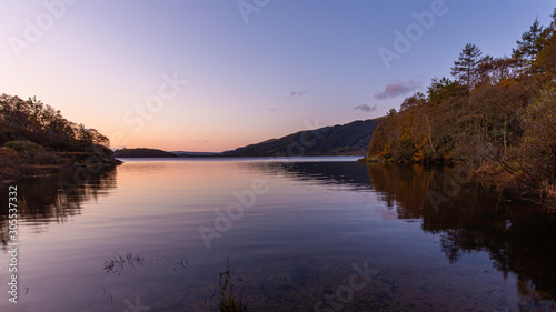 Sunrise at Loch Lomond  Scotland UK..Beautiful landscape of Scottish Highlands.Tranquil morning scene with reflection of autumn coloured trees in calm lake surface.