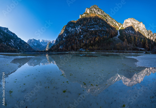 Autumn peaceful alpine lake Durrensee or Lago di Landro. Snow-capped Cristallo rocky mountain group behind, Dolomites, Italy, Europe. Seasonal and nature beauty concept. People and cars unrecognizable photo