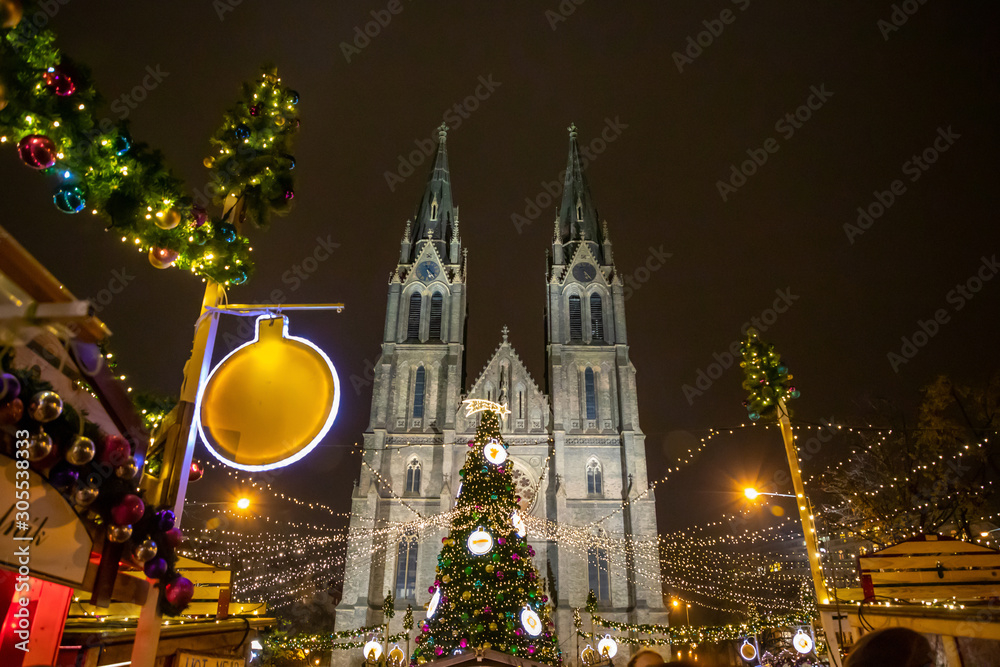Christmas fair and decorated Christmas tree in Namesti Miru Square against the building of the St. Ludmila Church, Prague, Czech Republic