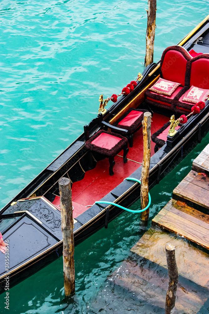 gondola moored near wooden poles awaiting tourists in Venice, Italy