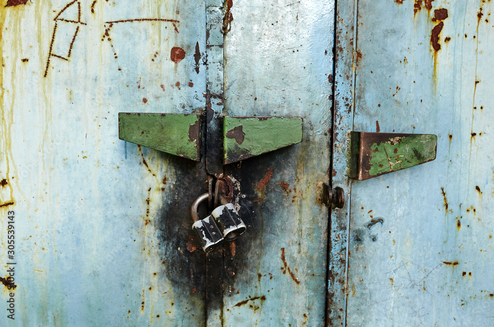 Worn metal door and padlock with scratches and cracks. Grunge texture of old rusty metal Worn metal door and padlock with scratches and cracks. Grunge texture of old rusty metal