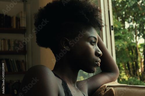 Side view of African American mysterious disappointed resentful sad woman looking out windows photo