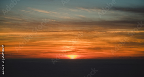 From above blurred gray horizon with hiding sun under beautiful colorful clouds on sky with wonderful transition at dusk photo
