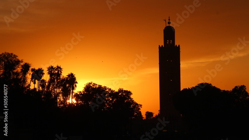 Panoramic view of the Orange Sunset in the tower of the Marrakech square from a terrace and the sun in the background. Morocco