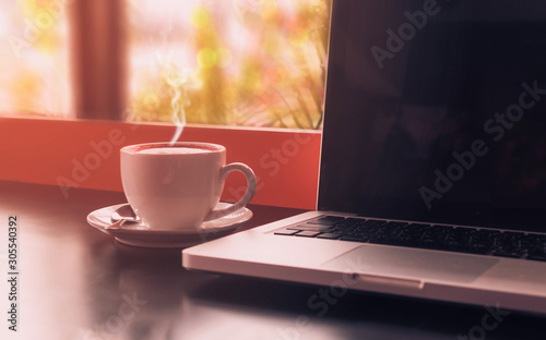 cup of coffee with laptop on wooden table