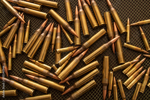 Many bullets (calibre .338 and .223) on a table with a green net