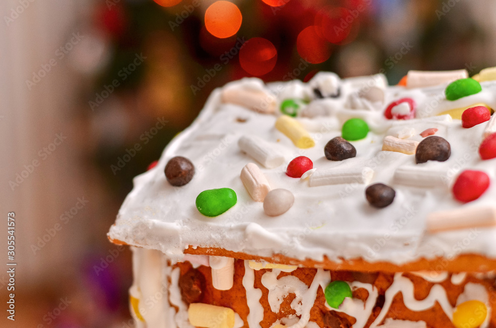 Homemade gingerbread house on the background of Christmas tree and lights. Homemade gingerbread house on the background of Christmas tree and lights.