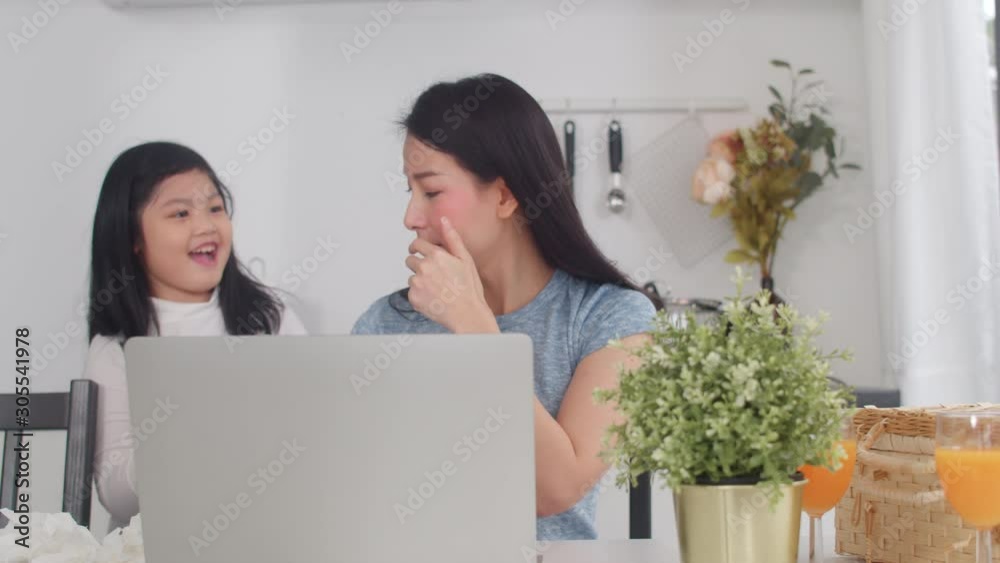 Young Asian business woman serious, stress, tired and sick while working on laptop at home. Daughter give water for her mother while working hard in modern kitchen at house in the morning concept. Young Asian business woman serious, stress, tired and sick while working on laptop at home. Daughter give water for her mother while working hard in modern kitchen at house in the morning concept.