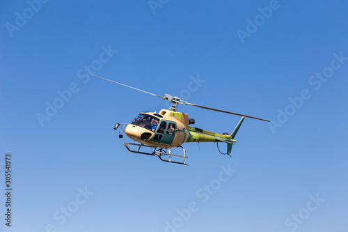A helicopter in flight on a sunny day. The helicopter has not yet been painted permanently.