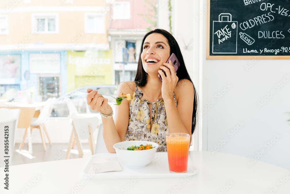 Cheerful woman with healthy food talking on smartphone in cafe Cheerful woman with healthy food talking on smartphone in cafe