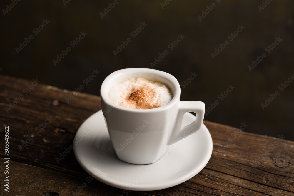 From above delicious fragrant brown beverage with white foam in ceramic cup on wooden table From above delicious fragrant brown beverage with white foam in ceramic cup on wooden table