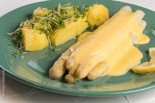 white asparagus poured with .hollandaise sauce, potatoes with chives and sprouts.
