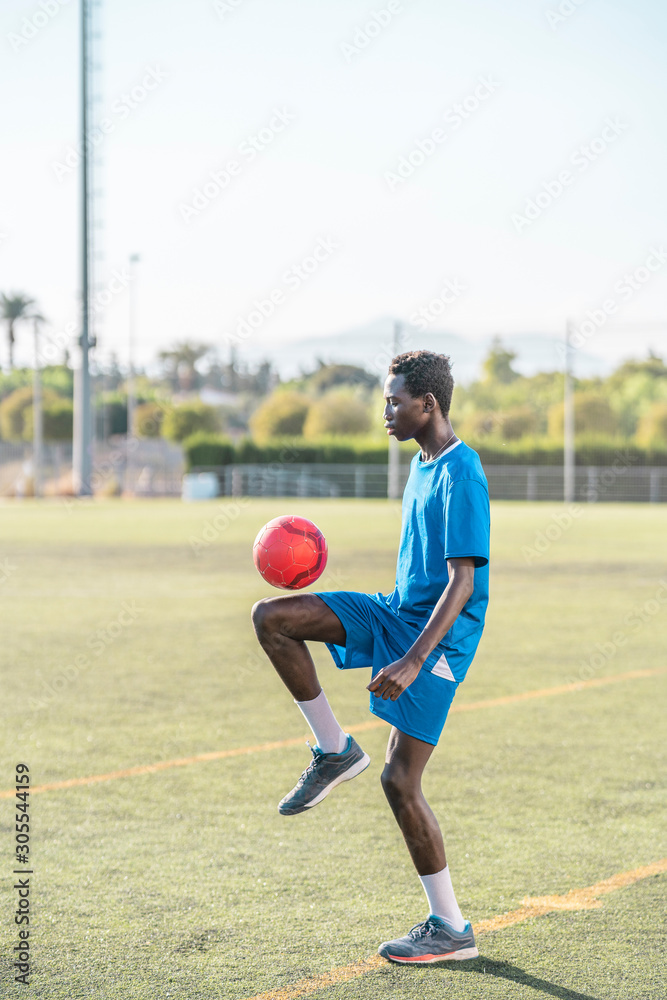 Ethnic teenager juggling football ball Ethnic teenager juggling football ball