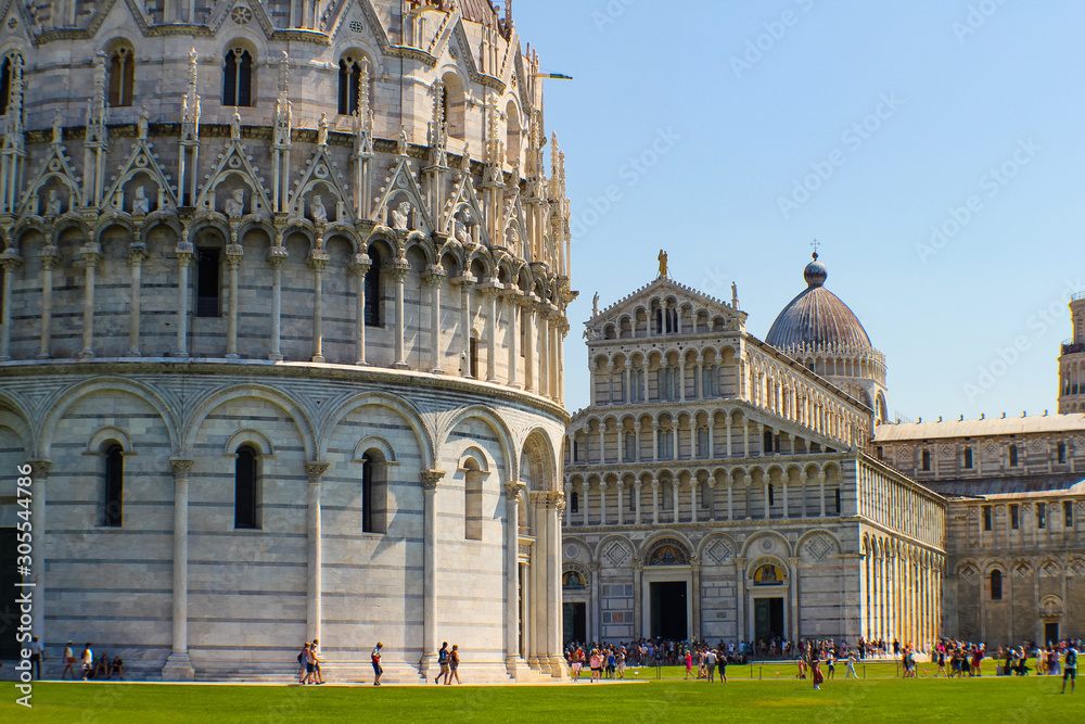 view of the baptistery of Pisa and behind the cathedral during a sunny day