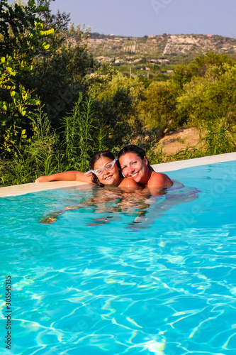 mom and daughter enjoying a swim in the pool at a resort in Sicily during the summer, Italy © stefano