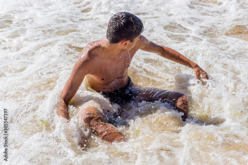 A young guy swims in the spray of the sea. He is laughs and scream..