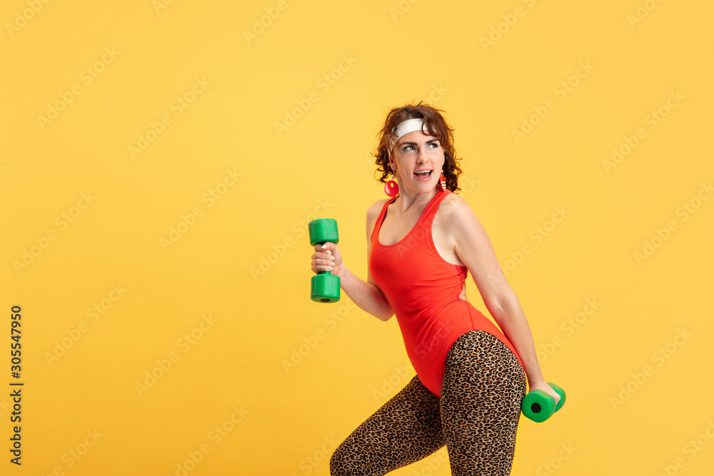 Young caucasian plus size female model's training on yellow background. Copyspace. Concept of sport, healthy lifestyle, body positive, fashion, style. Stylish woman practicing with the weights. Young caucasian plus size female model's training on yellow background. Copyspace. Concept of sport, healthy lifestyle, body positive, fashion, style. Stylish woman practicing with the weights.
