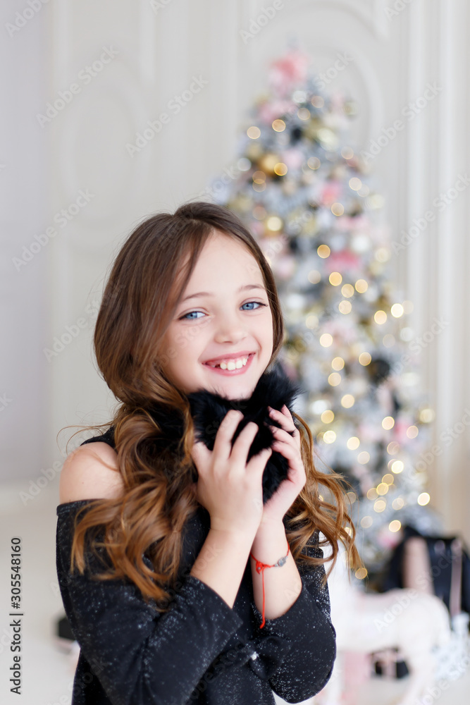   Beautiful little girl with long hair wearing black fur headphones.  Little Girl in a Fur Headphones.  Merry Christmas and Happy New Year.  Christmas celebration.
