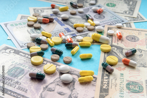 Colorful, variety pills and capsules on dollars banknotes. concept of high cost treatment, preservation of health and medical insurance
