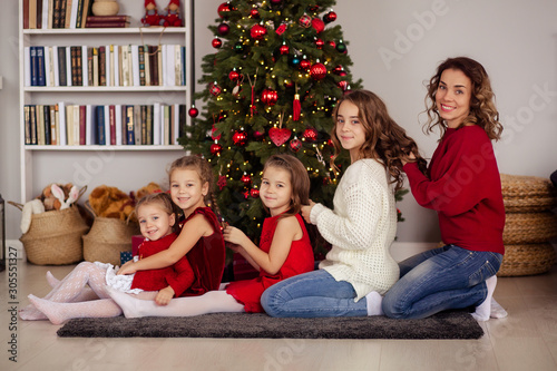 sisters and mothers braid each other around a new year tree and all together squeeze out a happy christmas and a new year, a happy family, parents and children