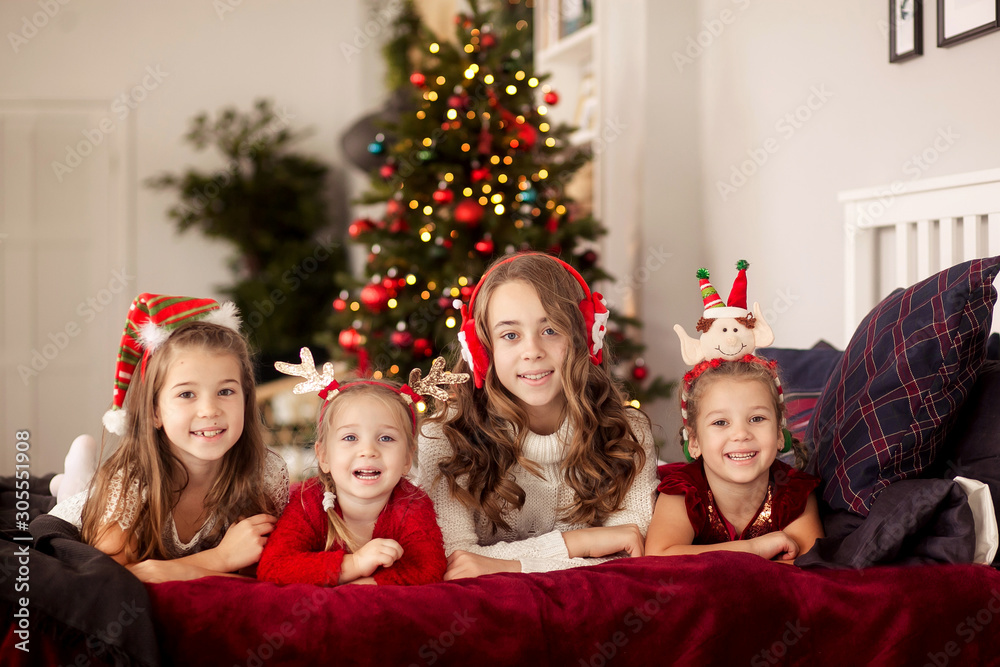 four happy cute sisters are lying on the bed, New Year is a happy Christmas, girls in beautiful dresses and new year's headbands, happy family four happy cute sisters are lying on the bed, New Year is a happy Christmas, girls in beautiful dresses and new year's headbands, happy family