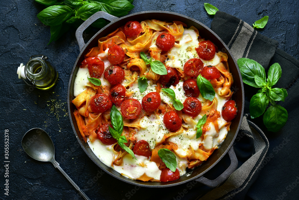 Pasta casserole with tomatoes and mozzarella cheese in a cast iron pan. Top view with copy space. - obrazy, fototapety, plakaty 