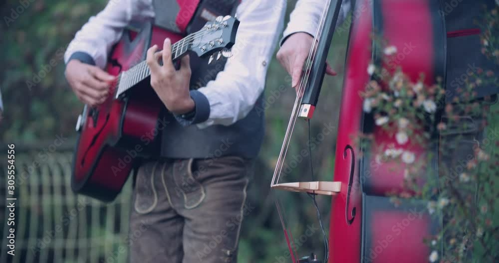 Close up slow motion shot, musician in traditional music costume playing guitar, double bass in background, 4K. Close up slow motion shot, musician in traditional music costume playing guitar, double bass in background, 4K.