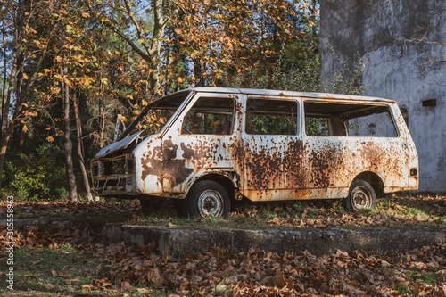 Old abandoned rusty car in a park.