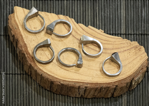 curved nails turned into rings, exposed on a wooden plate