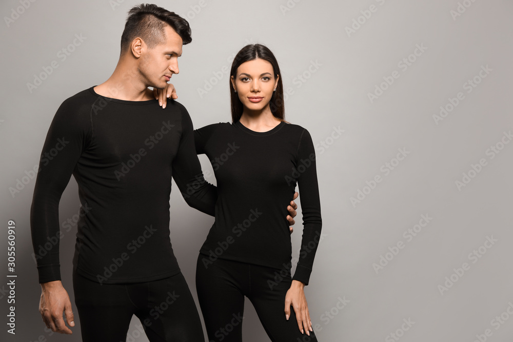 Couple wearing thermal underwear on grey background. Space for text Couple wearing thermal underwear on grey background. Space for text