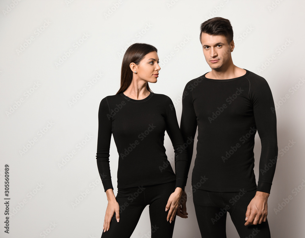 Couple wearing thermal underwear on light grey background Couple wearing thermal underwear on light grey background
